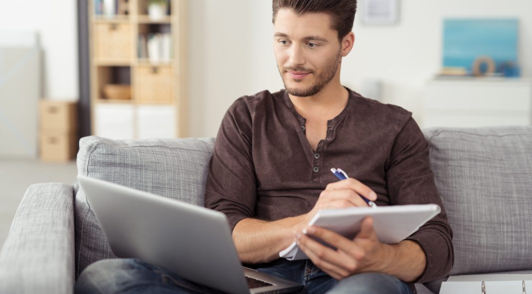 mann mit laptop und unterlagen in seiner wohnung